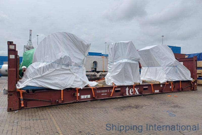 A container at a shipping yard with covered cargo and some workers, under a cloudy sky.